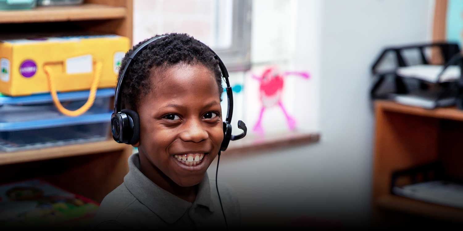 A smiling student wearing a headset in a classroom